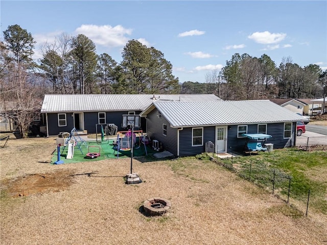 view of front facade featuring fence, a fire pit, a playground, and metal roof