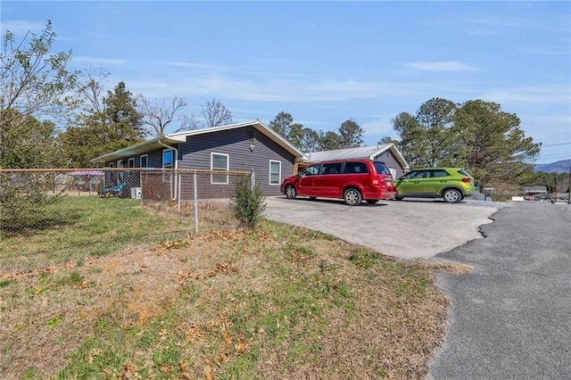 view of property exterior with aphalt driveway, a yard, and fence