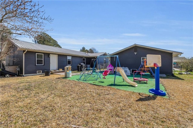 back of property with a lawn, metal roof, and a playground