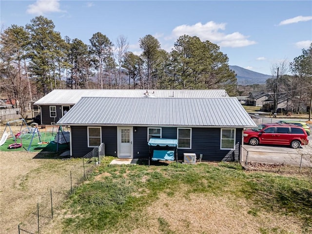 view of front of home with a mountain view, metal roof, a front yard, and fence