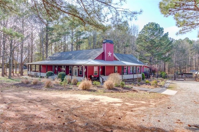 view of front of home with fence, covered porch, and a chimney