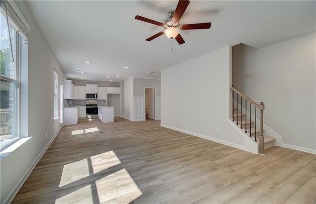 unfurnished living room with light hardwood / wood-style flooring, ceiling fan, and a healthy amount of sunlight