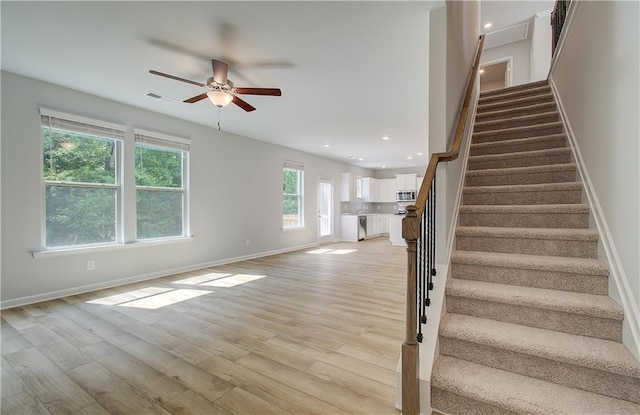 stairway with hardwood / wood-style floors and ceiling fan