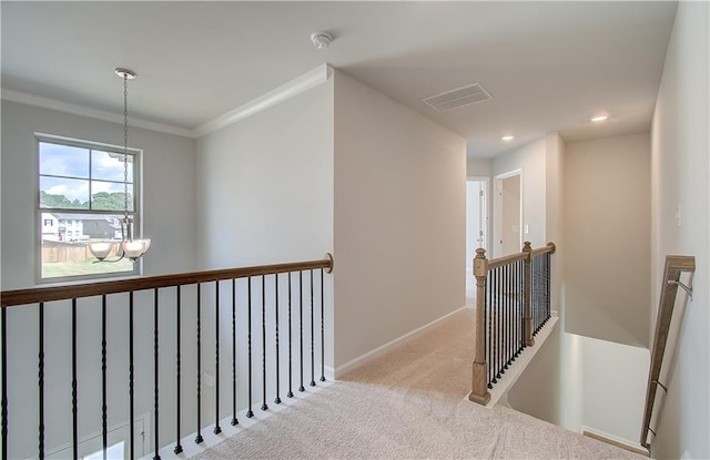 hall with light colored carpet, an inviting chandelier, and crown molding