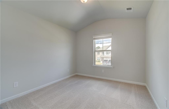 spare room featuring carpet flooring and vaulted ceiling