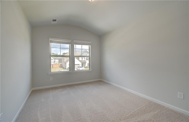 unfurnished room featuring light colored carpet and vaulted ceiling