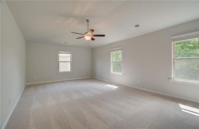 carpeted empty room with a wealth of natural light and ceiling fan