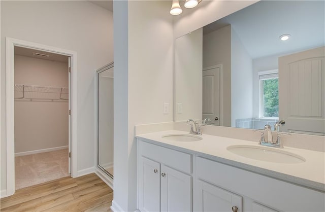 bathroom with wood-type flooring, vanity, and a shower with door