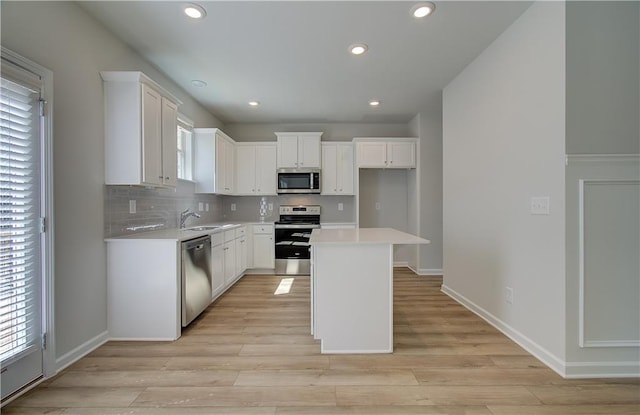 kitchen featuring a center island, light wood-type flooring, white cabinetry, and stainless steel appliances