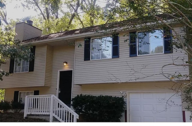 bi-level home featuring a chimney and an attached garage