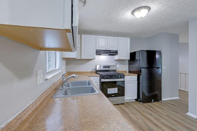 5295 Old Trail Cir, Stone Mountain, GA 30088 - kitchen with stainless steel gas range oven, under cabinet range hood, a sink, freestanding refrigerator, and white cabinets