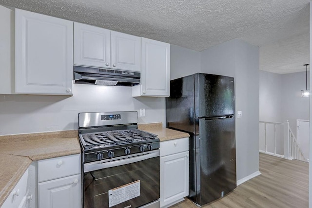 5295 Old Trail Cir, Stone Mountain, GA 30088 - kitchen with freestanding refrigerator, stainless steel gas range oven, under cabinet range hood, light wood-style flooring, and light countertops