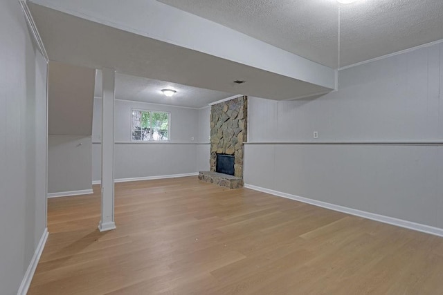 5295 Old Trail Cir, Stone Mountain, GA 30088 - below grade area featuring a textured ceiling, light wood-style floors, a fireplace, and baseboards