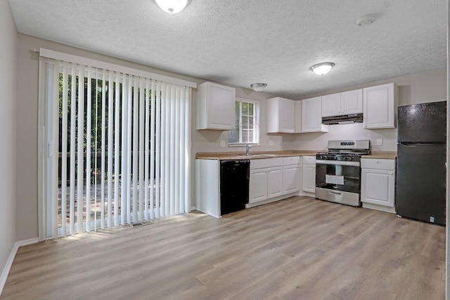 5295 Old Trail Cir, Stone Mountain, GA 30088 - kitchen with black appliances, light wood-type flooring, healthy amount of natural light, white cabinetry, and a textured ceiling