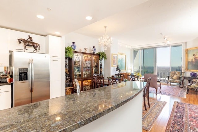 kitchen with white cabinets, stainless steel refrigerator with ice dispenser, light hardwood / wood-style floors, and decorative light fixtures