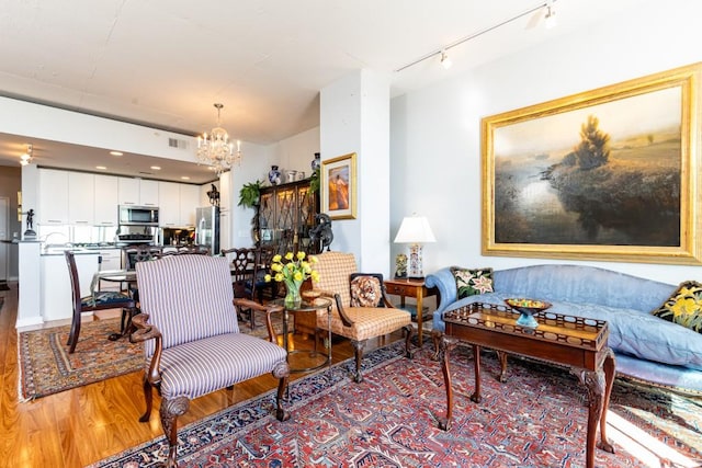 living room with hardwood / wood-style floors, track lighting, and a chandelier