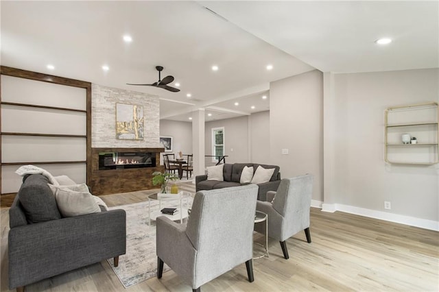 living room featuring light hardwood / wood-style floors, a fireplace, and ceiling fan