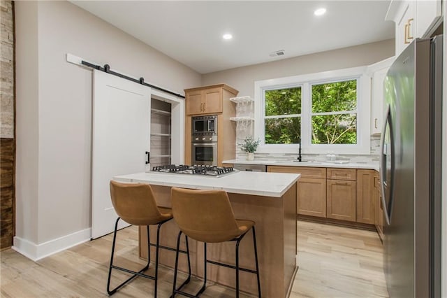1510 Mims St SW, Atlanta, GA 30314 - kitchen with visible vents, light wood-style flooring, a kitchen breakfast bar, a center island, and stainless steel appliances