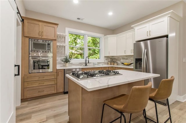 kitchen with a center island, light stone counters, stainless steel appliances, and light hardwood / wood-style floors