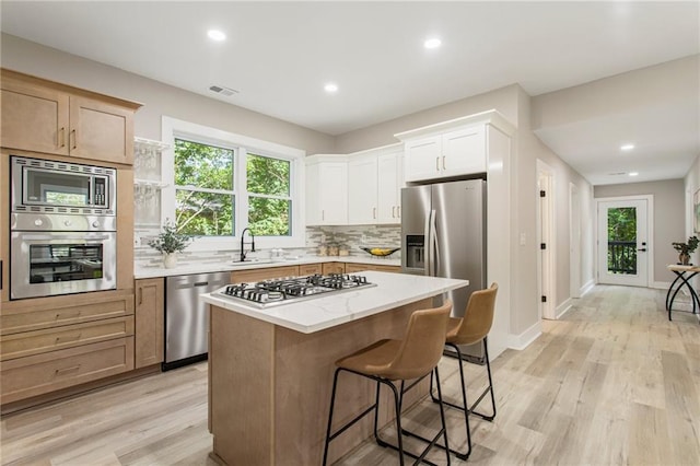 kitchen with a center island, appliances with stainless steel finishes, light wood-type flooring, and plenty of natural light