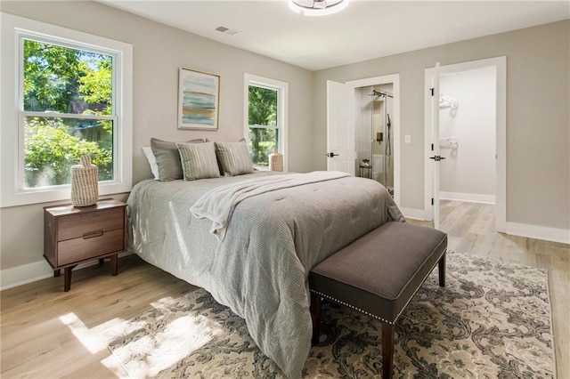 bedroom with light hardwood / wood-style flooring, multiple windows, and a walk in closet