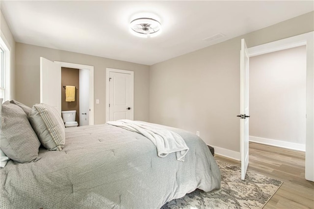 bedroom featuring ensuite bathroom and light wood-type flooring