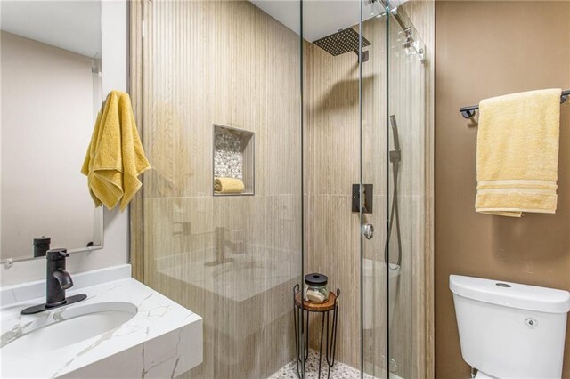 bathroom with walk in shower, sink, and toilet