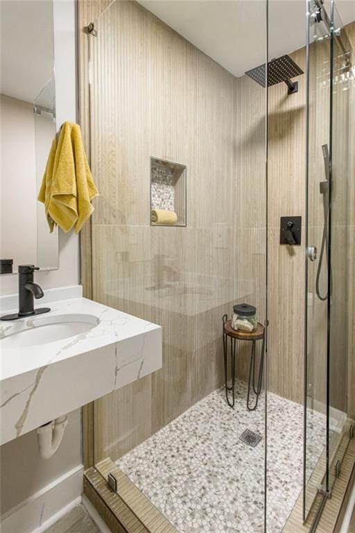 bathroom with a shower with shower door and sink