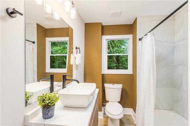 full bathroom featuring vanity, shower / bathtub combination with curtain, hardwood / wood-style flooring, and toilet