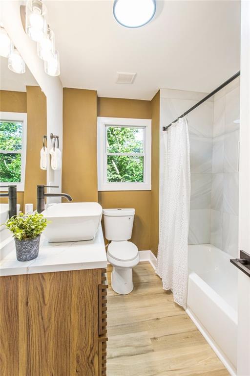 full bathroom with hardwood / wood-style flooring, toilet, vanity, and plenty of natural light