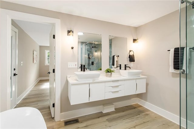 bathroom featuring wood-type flooring, double sink vanity, and an enclosed shower