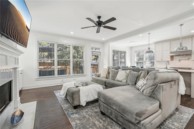 kitchen with a kitchen island with sink, high quality appliances, dark wood-type flooring, sink, and white cabinetry