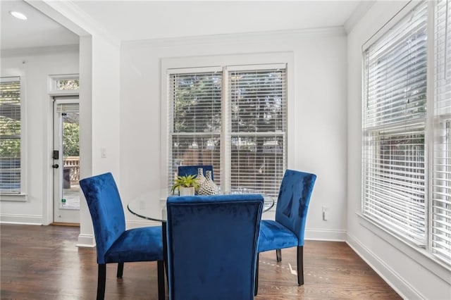 dining space with dark wood-type flooring, crown molding, and an inviting chandelier