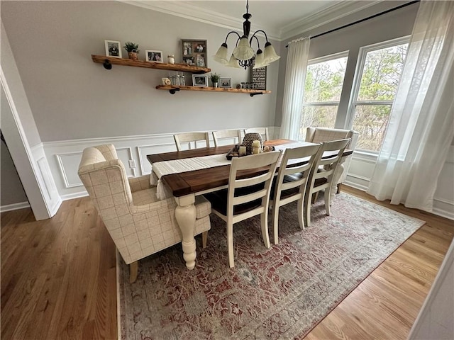 dining room with ornamental molding, an inviting chandelier, and light wood-type flooring