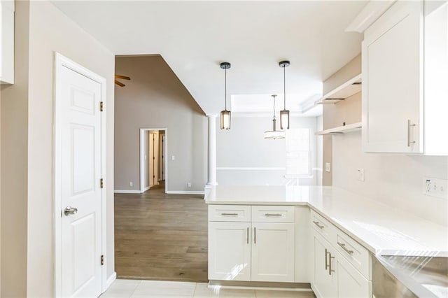 kitchen with white cabinetry, decorative light fixtures, decorative columns, and light wood-type flooring