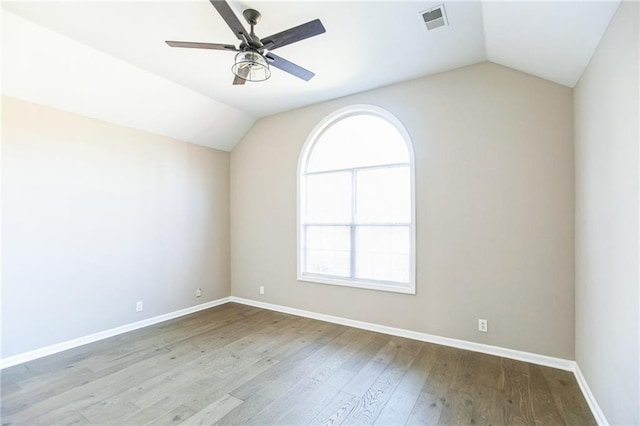 empty room with ceiling fan, vaulted ceiling, and light wood-type flooring