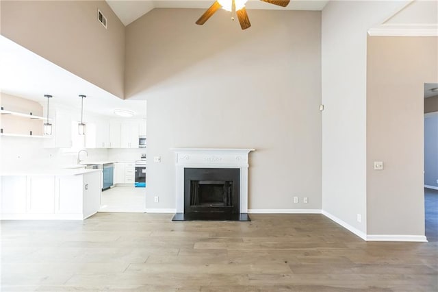 unfurnished living room with sink, high vaulted ceiling, light hardwood / wood-style floors, and ceiling fan