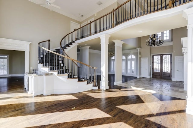 foyer with hardwood / wood-style flooring, crown molding, and ornate columns