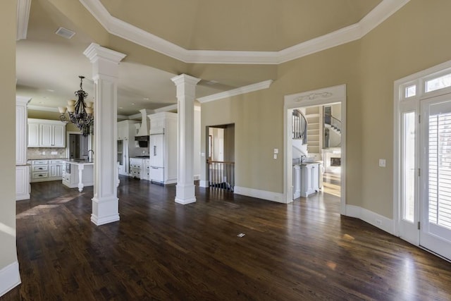 unfurnished living room featuring crown molding, dark wood-type flooring, and decorative columns