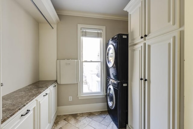 washroom featuring ornamental molding, cabinets, and stacked washer / dryer