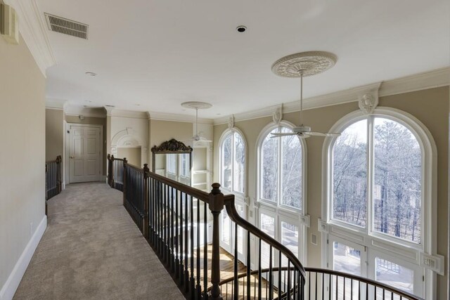 corridor featuring crown molding and light carpet