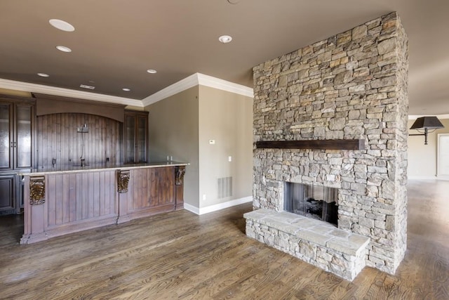 kitchen featuring crown molding, dark brown cabinets, dark hardwood / wood-style floors, and a fireplace