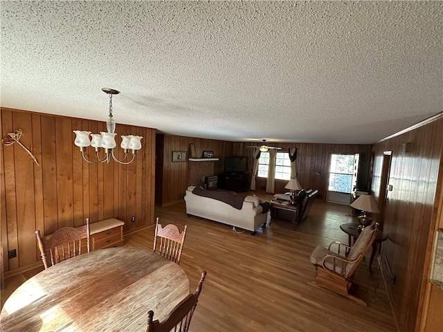 dining area featuring dark hardwood / wood-style floors, a textured ceiling, a notable chandelier, and wooden walls