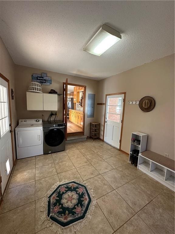 laundry area with cabinets, light tile patterned floors, washing machine and clothes dryer, and a textured ceiling