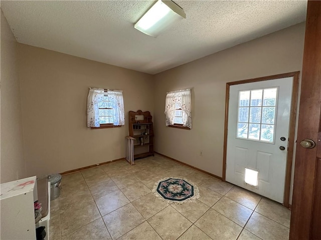 foyer with a textured ceiling and light tile patterned floors