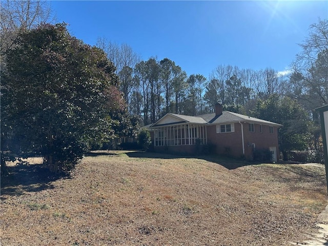 view of home's exterior with a yard and a sunroom