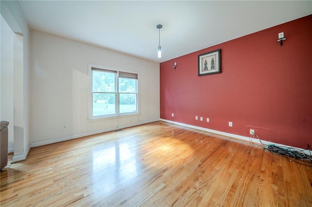 spare room featuring light wood-style floors and baseboards