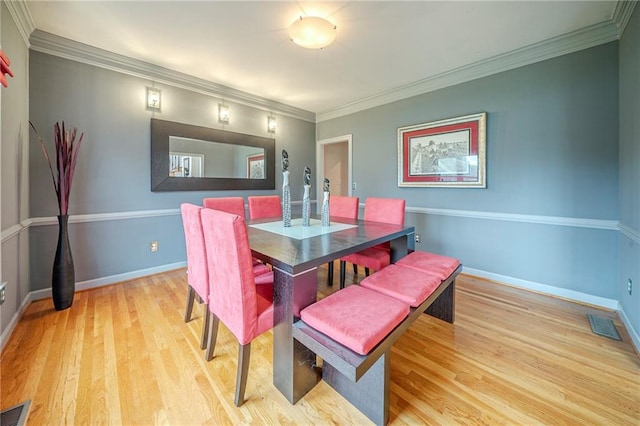 dining room with crown molding, baseboards, light wood-type flooring, and visible vents