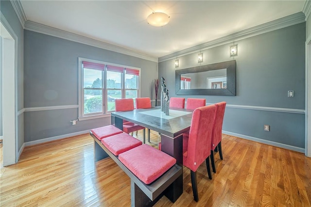 dining room with light wood finished floors, crown molding, and baseboards
