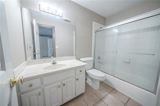 bathroom featuring toilet, vanity, visible vents, tile patterned floors, and enclosed tub / shower combo
